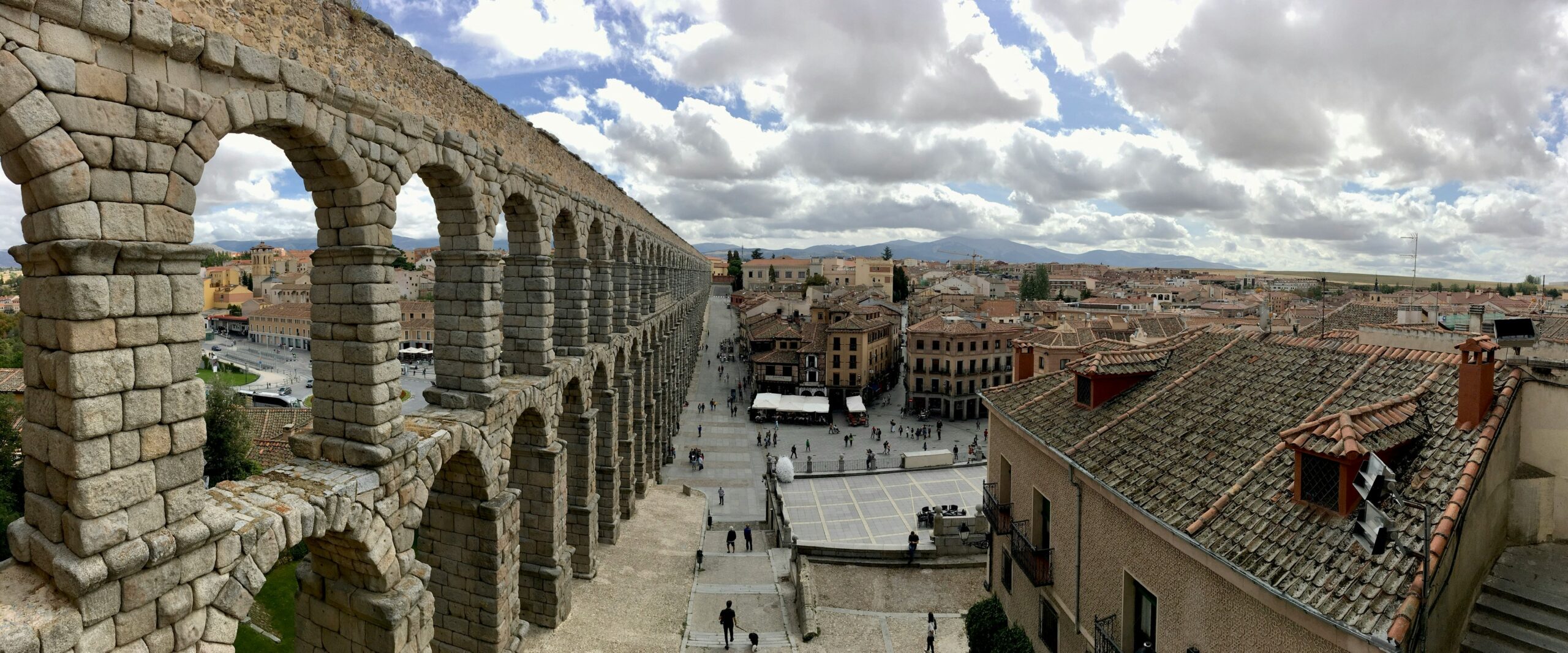 Bird view of the Segovia Aqueduct with half of the ancient Roman structure and half showing the adjacent cityscape.